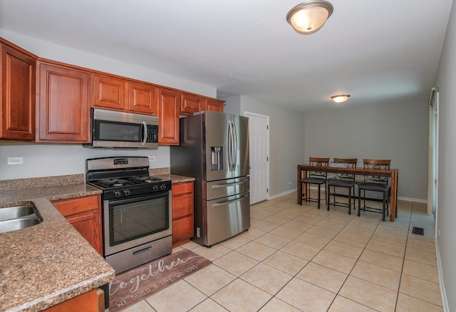17801 Dogwood Ln, Hazel Crest, IL 60429 - kitchen featuring appliances with stainless steel finishes, light tile patterned flooring, and brown cabinets