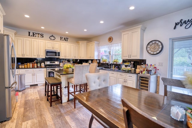 281 Fox Chase Dr N, Oswego, IL 60543 - kitchen featuring stainless steel appliances, dark countertops, wine cooler, tasteful backsplash, and light wood-style floors