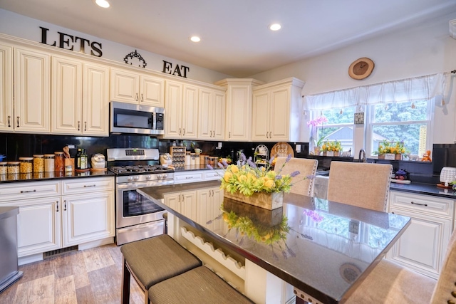 281 Fox Chase Dr N, Oswego, IL 60543 - kitchen with stainless steel appliances, backsplash, recessed lighting, a kitchen bar, and light wood-type flooring