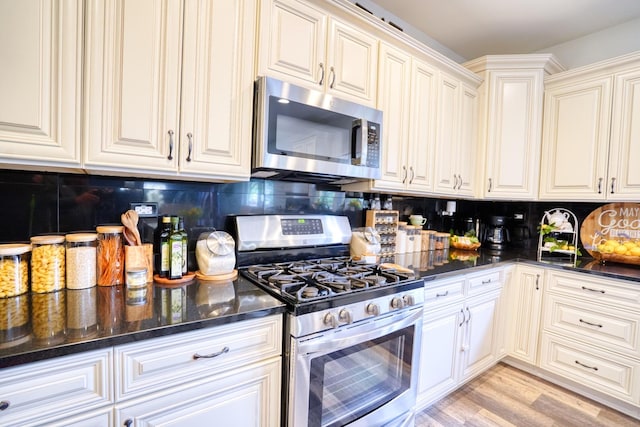 281 Fox Chase Dr N, Oswego, IL 60543 - kitchen featuring stainless steel appliances, backsplash, light wood-type flooring, dark stone countertops, and white cabinetry