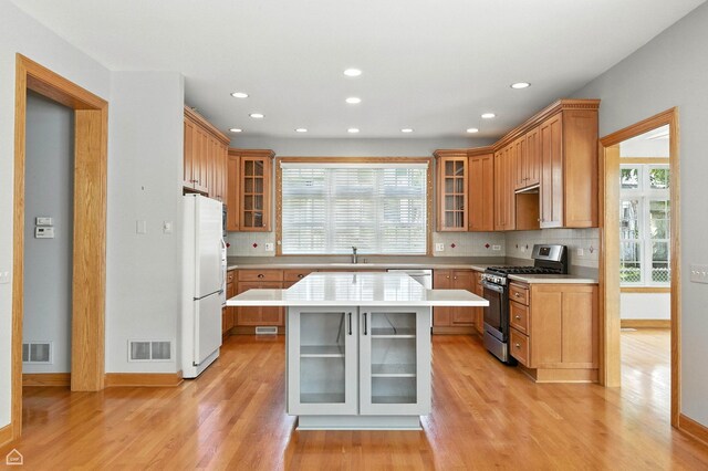 4829 Linscott Ave, Downers Grove, IL 60515 - kitchen with stainless steel range with gas stovetop, freestanding refrigerator, light wood finished floors, light countertops, and decorative backsplash