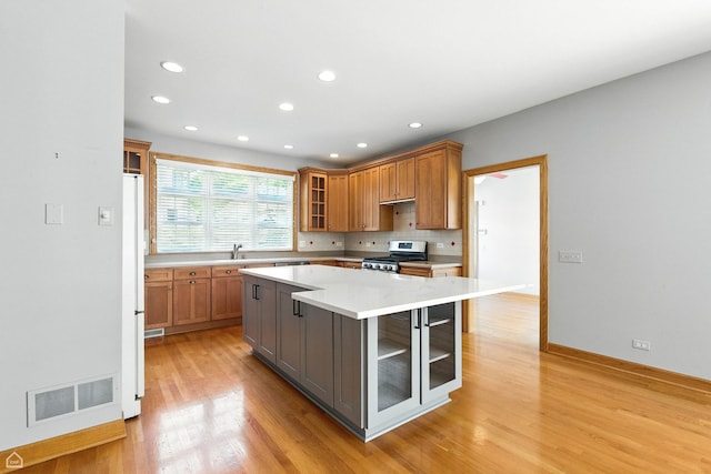 4829 Linscott Ave, Downers Grove, IL 60515 - kitchen featuring stainless steel stove, light wood finished floors, light countertops, recessed lighting, and glass insert cabinets