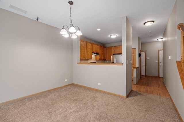 2442 Oneida Ln, Naperville, IL 60563 - kitchen with freestanding refrigerator, under cabinet range hood, light carpet, a chandelier, and hanging light fixtures