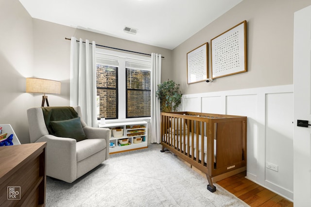 2636 N Fairfield Ave Unit 2N, Chicago, IL 60647 - bedroom with a crib, wood finished floors, and a wainscoted wall