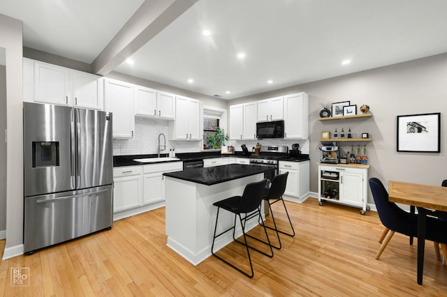 2636 N Fairfield Ave Unit 2N, Chicago, IL 60647 - kitchen featuring stainless steel appliances, tasteful backsplash, light wood-style floors, white cabinetry, and a breakfast bar