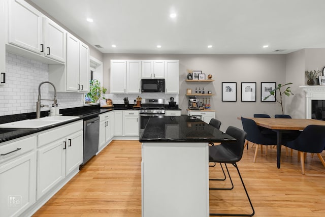 2636 N Fairfield Ave Unit 2N, Chicago, IL 60647 - kitchen with appliances with stainless steel finishes, a kitchen bar, a center island, light wood finished floors, and white cabinets