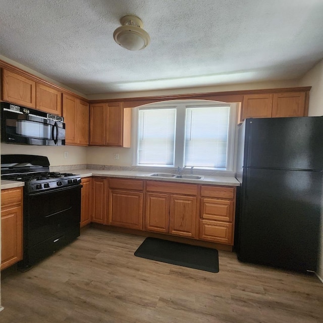 1223 Putnam St, Peru, IL 61354 - kitchen with black appliances, light countertops, light wood-style floors, a textured ceiling, and brown cabinets