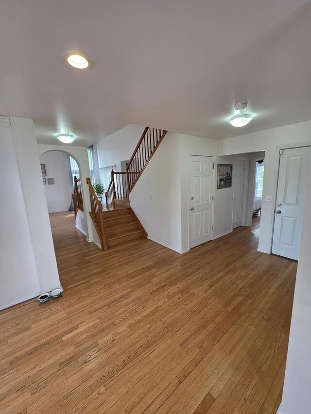 7943 Dada Dr, Gurnee, IL 60031 - unfurnished living room with arched walkways, stairway, and light wood-style floors