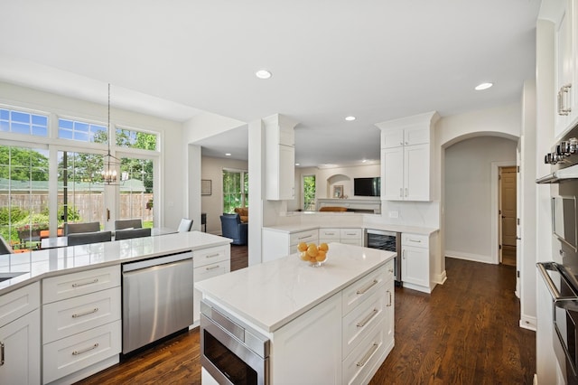 1318 Bennington Ct, Glenview, IL 60026 - kitchen with beverage cooler, appliances with stainless steel finishes, a center island, arched walkways, and white cabinets