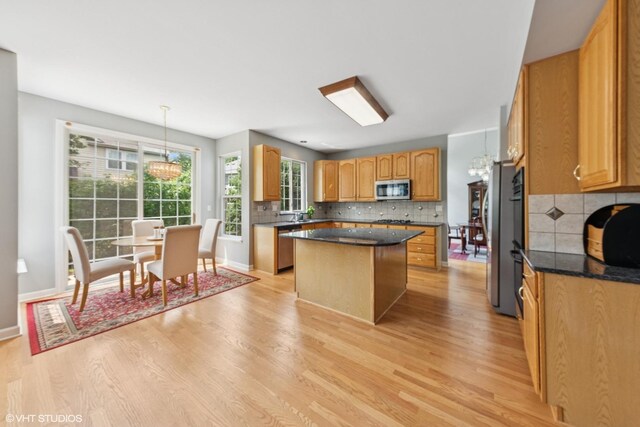 2397 Pebble Beach Ln, Riverwoods, IL 60015 - kitchen with appliances with stainless steel finishes, a kitchen island, light wood-style flooring, and tasteful backsplash