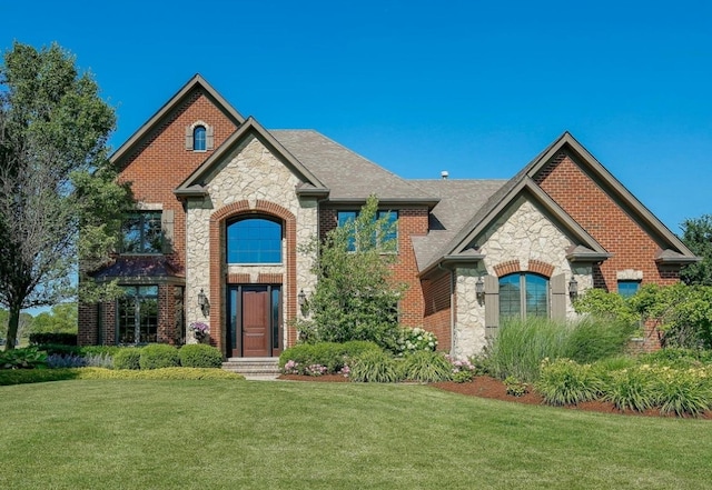 4213 Steam Mill Ct, Oswego, IL 60543 - french country inspired facade featuring stone siding, a front lawn, brick siding, and a shingled roof