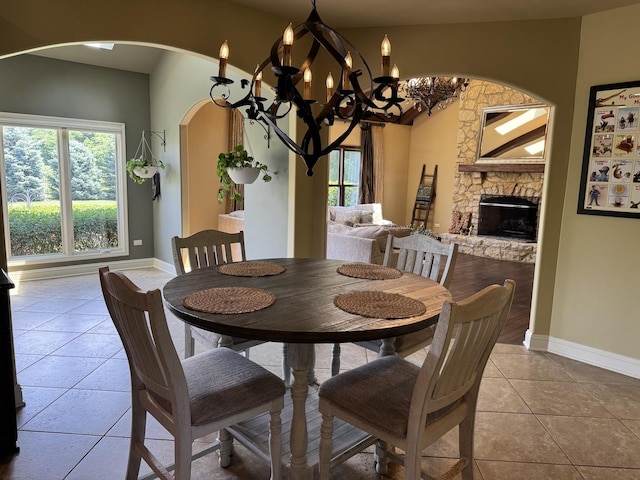 4213 Steam Mill Ct, Oswego, IL 60543 - tiled dining space featuring arched walkways, a chandelier, and a stone fireplace
