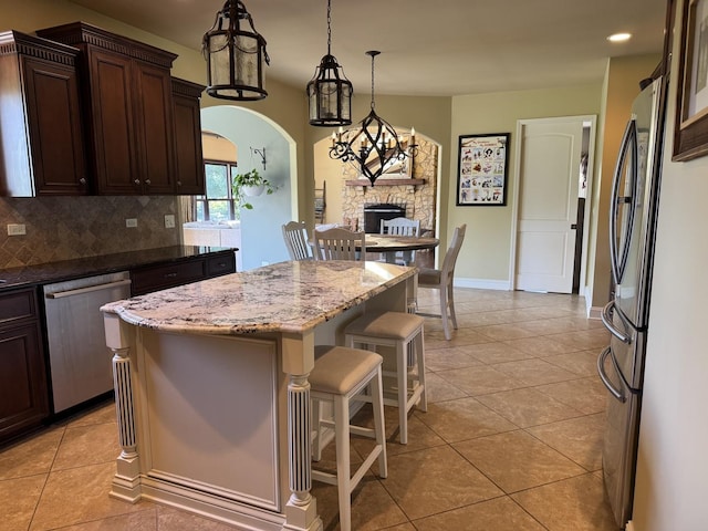 4213 Steam Mill Ct, Oswego, IL 60543 - kitchen featuring appliances with stainless steel finishes, dark brown cabinets, light tile patterned floors, backsplash, and a kitchen breakfast bar