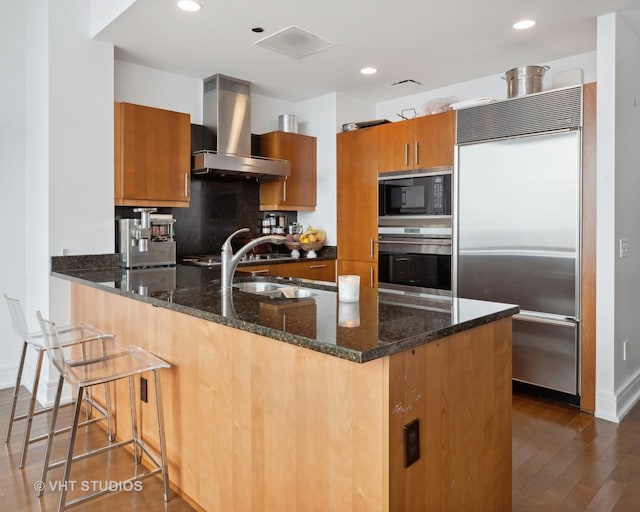 401 N Wabash Ave Unit 30E, Chicago, IL 60611 - kitchen with built in appliances, wall chimney range hood, dark stone counters, a peninsula, and recessed lighting