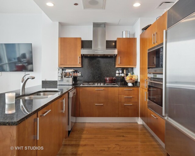 401 N Wabash Ave Unit 30E, Chicago, IL 60611 - kitchen with built in appliances, wall chimney exhaust hood, brown cabinetry, wood finished floors, and recessed lighting