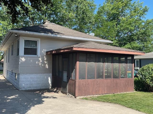 1322 N Prairie Ave, Joliet, IL 60435 - view of front facade with a sunroom and a shingled roof
