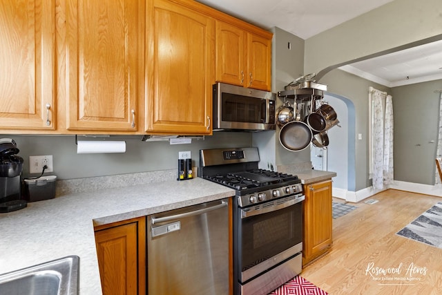 409 E Main St, Peotone, IL 60468 - kitchen featuring appliances with stainless steel finishes, light wood-type flooring, light countertops, ornamental molding, and arched walkways