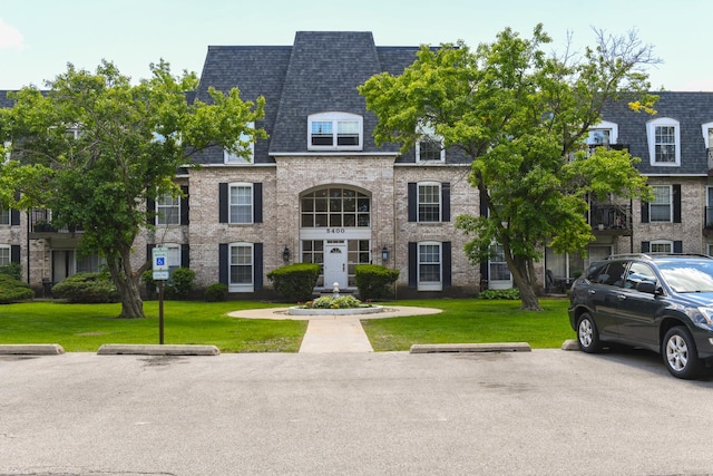 5400 Carriageway Dr Unit 315, Rolling Meadows, IL 60008 - view of front of property with a front lawn, a shingled roof, brick siding, and uncovered parking