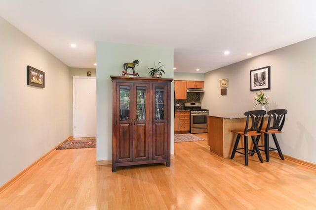 5400 Carriageway Dr Unit 315, Rolling Meadows, IL 60008 - kitchen with stainless steel gas range, light wood finished floors, a kitchen bar, recessed lighting, and a peninsula