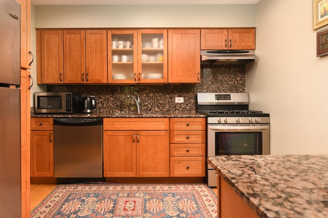 5400 Carriageway Dr Unit 315, Rolling Meadows, IL 60008 - kitchen with stainless steel appliances, under cabinet range hood, dark stone counters, backsplash, and brown cabinets