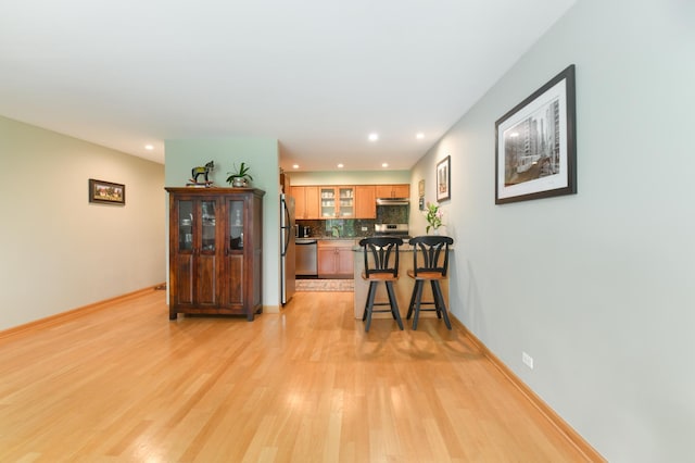 5400 Carriageway Dr Unit 315, Rolling Meadows, IL 60008 - kitchen with appliances with stainless steel finishes, light wood finished floors, tasteful backsplash, glass insert cabinets, and a breakfast bar area