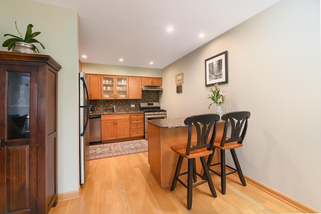 5400 Carriageway Dr Unit 315, Rolling Meadows, IL 60008 - kitchen featuring stainless steel appliances, a peninsula, light wood-style flooring, a breakfast bar, and glass insert cabinets