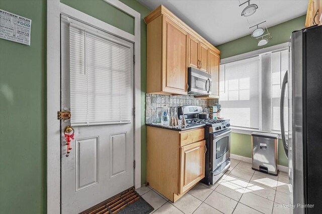 6121 N Hoyne Ave Unit 1S, Chicago, IL 60659 - kitchen featuring appliances with stainless steel finishes, light tile patterned floors, dark countertops, and backsplash