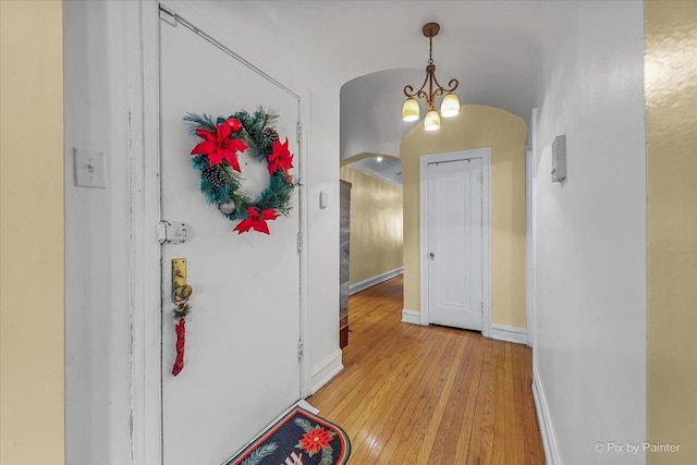 6121 N Hoyne Ave Unit 1S, Chicago, IL 60659 - hallway with arched walkways, light wood-style flooring, and a chandelier