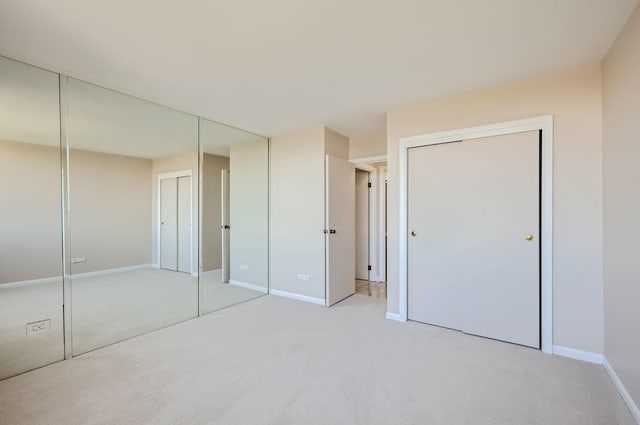 20 N Tower Rd Unit 12M, Oak Brook, IL 60523 - unfurnished bedroom featuring multiple closets and light carpet