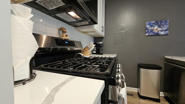 16 Forest Ln, Cary, IL 60013 - kitchen featuring stainless steel range with gas cooktop, decorative backsplash, light wood-style flooring, white cabinets, and light countertops