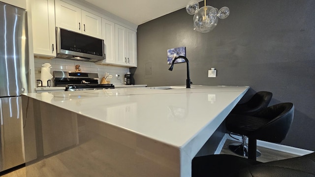 16 Forest Ln, Cary, IL 60013 - kitchen featuring appliances with stainless steel finishes, tasteful backsplash, white cabinetry, and a kitchen breakfast bar