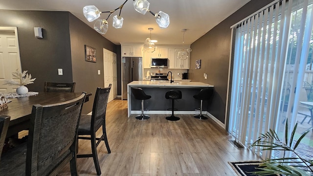 16 Forest Ln, Cary, IL 60013 - kitchen with appliances with stainless steel finishes, white cabinetry, wood finished floors, light countertops, and a peninsula