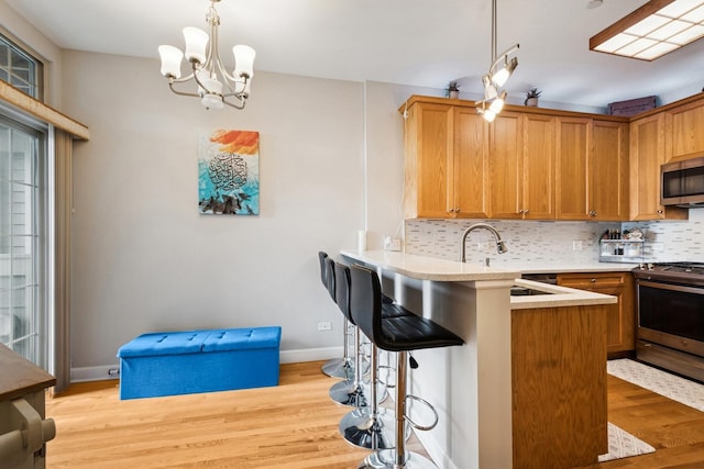 8471 Callie Ave, Morton Grove, IL 60053 - kitchen featuring appliances with stainless steel finishes, light wood-style flooring, decorative backsplash, a breakfast bar area, and light countertops