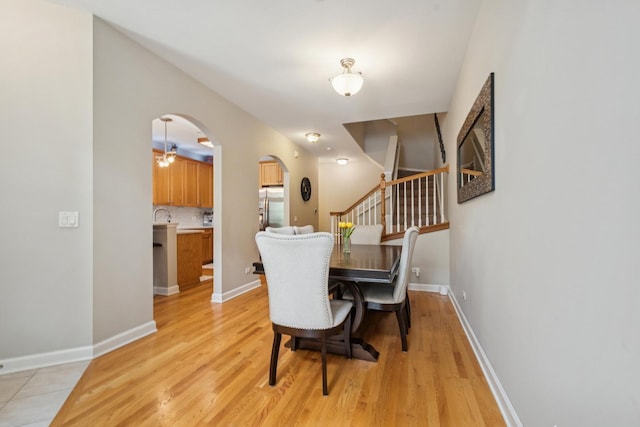 8471 Callie Ave, Morton Grove, IL 60053 - dining room featuring arched walkways, light wood-style floors, and stairs