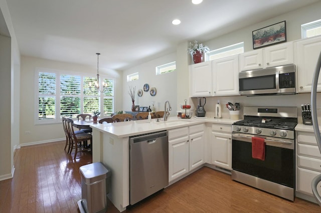 13159 Shirley Ln, Huntley, IL 60142 - kitchen featuring appliances with stainless steel finishes, a peninsula, wood finished floors, recessed lighting, and white cabinets