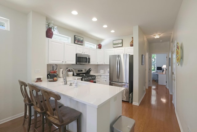 13159 Shirley Ln, Huntley, IL 60142 - kitchen with appliances with stainless steel finishes, a peninsula, a breakfast bar area, recessed lighting, and wood-type flooring