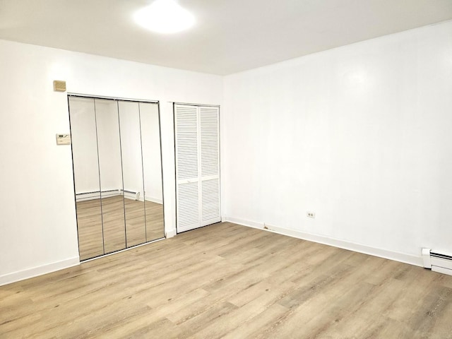 543 E 60th St Unit 1, Chicago, IL 60637 - unfurnished bedroom with wood finished floors, two closets, and a baseboard radiator