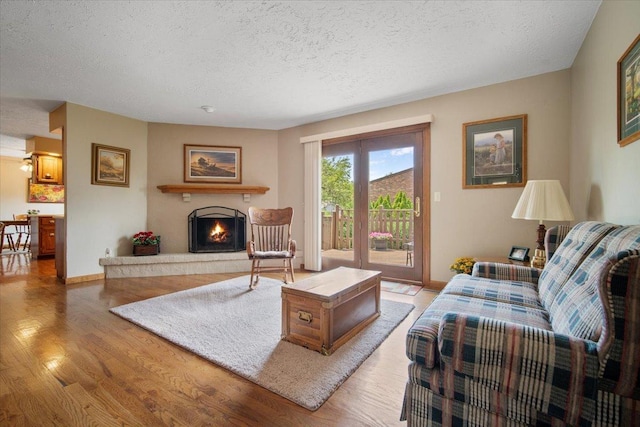 2210 Hedgewood Dr, Bloomington, IL 61704 - living area featuring a textured ceiling, light wood-type flooring, and a warm lit fireplace