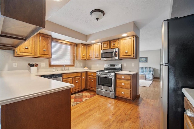 2210 Hedgewood Dr, Bloomington, IL 61704 - kitchen with appliances with stainless steel finishes, light countertops, a textured ceiling, light wood finished floors, and a peninsula