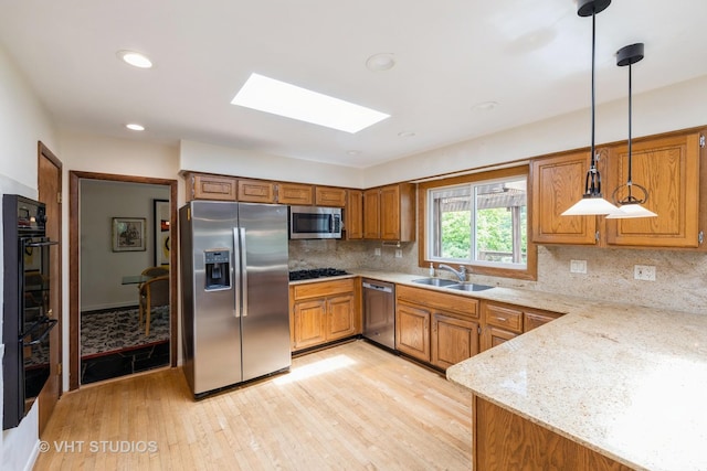 855 Beverly Pl, Lake Forest, IL 60045 - kitchen with appliances with stainless steel finishes, a skylight, brown cabinets, light wood finished floors, and hanging light fixtures