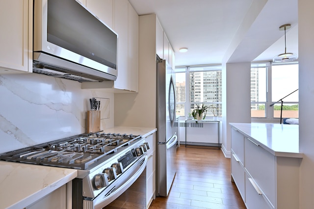3950 N Lake Shore Dr Unit 810B, Chicago, IL 60613 - kitchen featuring appliances with stainless steel finishes, radiator heating unit, white cabinetry, light wood finished floors, and light stone counters