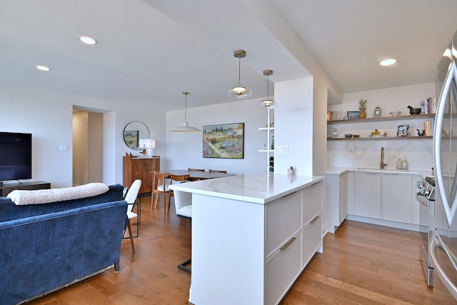 3950 N Lake Shore Dr Unit 810B, Chicago, IL 60613 - kitchen featuring a peninsula, open shelves, white cabinets, a kitchen breakfast bar, and light wood-type flooring
