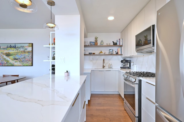 3950 N Lake Shore Dr Unit 810B, Chicago, IL 60613 - kitchen featuring stainless steel appliances, open shelves, light wood-style floors, light stone counters, and hanging light fixtures