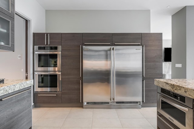 33 W Ontario St Unit Th5, Chicago, IL 60654 - kitchen with appliances with stainless steel finishes, dark brown cabinets, light tile patterned flooring, and glass insert cabinets