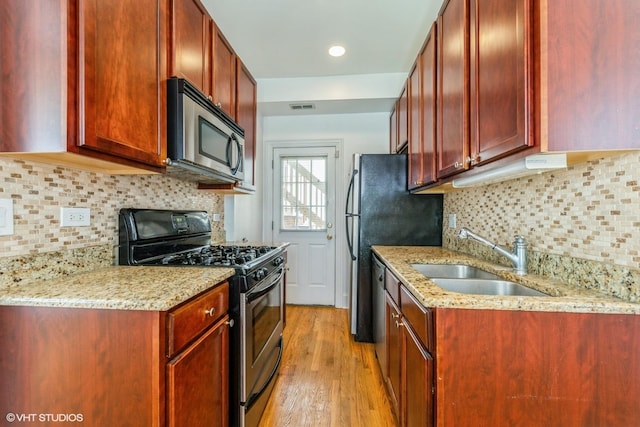 5412 N Kenmore Ave Unit 1W, Chicago, IL 60640 - kitchen with appliances with stainless steel finishes, dark brown cabinets, light wood finished floors, light stone counters, and backsplash
