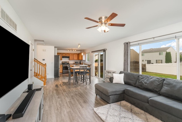1704 Cascade Ridge Dr, Plainfield, IL 60586 - living room featuring stairway, ceiling fan, light wood-style floors, and healthy amount of natural light