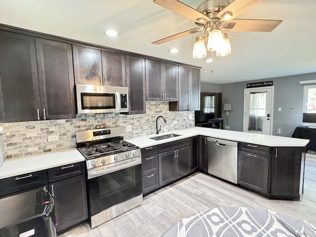 311 Edinburgh Dr, Lockport, IL 60441 - kitchen featuring appliances with stainless steel finishes, a peninsula, light wood-type flooring, decorative backsplash, and a ceiling fan