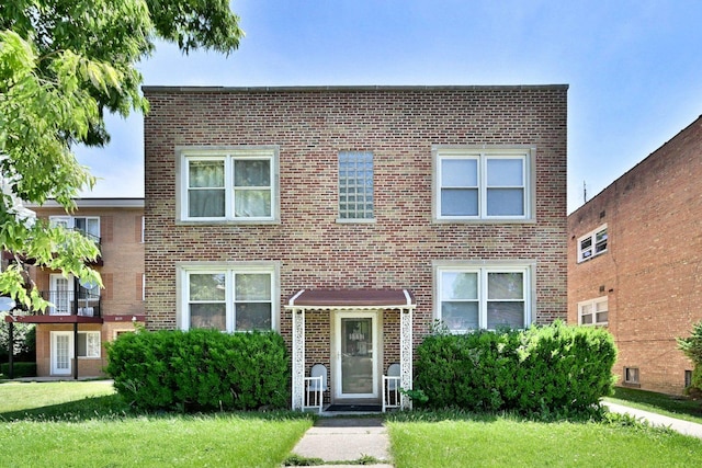 view of front facade with brick siding and a front yard