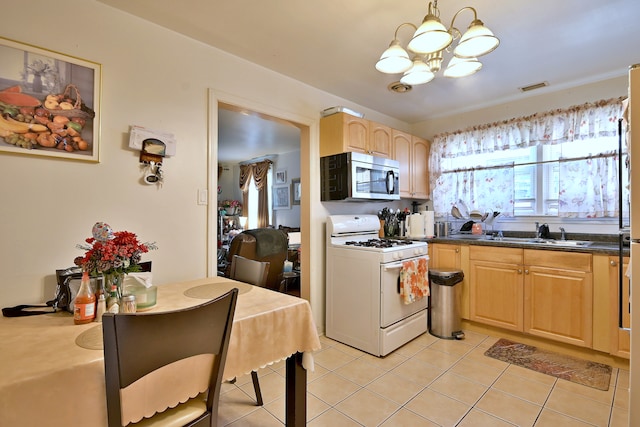 kitchen featuring stainless steel microwave, white gas range, a chandelier, light tile patterned floors, and dark countertops