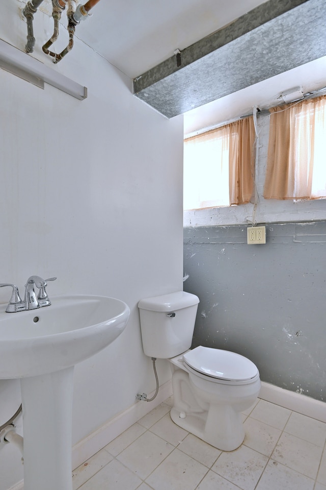 half bath with baseboards and tile patterned floors